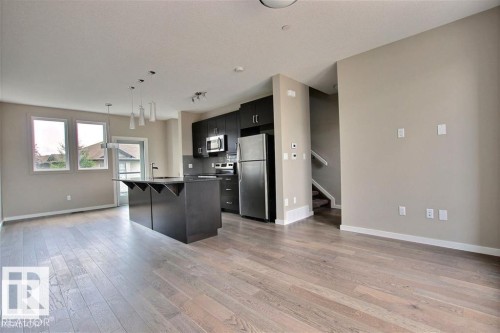 Kitchen featuring open floor plan, a kitchen bar, stainless steel appliances, and hanging light fixtures - 125 1304 Rutherford Road, Edmonton, AB - Indoor Photo Showing Kitchen