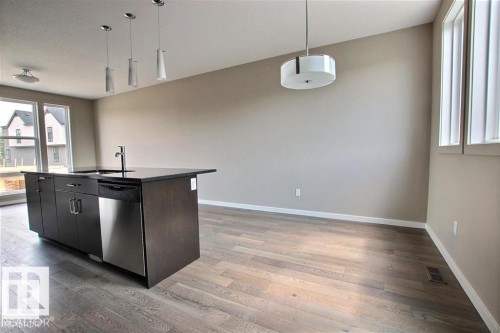 Kitchen with open floor plan, decorative light fixtures, dishwasher, a center island with sink, and light wood-style floors - 125 1304 Rutherford Road, Edmonton, AB - Indoor