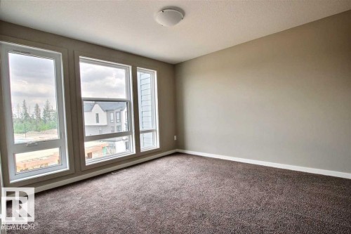 Carpeted empty room featuring baseboards and a textured ceiling - 125 1304 Rutherford Road, Edmonton, AB - Indoor Photo Showing Other Room