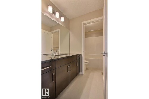 Bathroom featuring vanity, a textured ceiling, and shower / bathtub combination - 125 1304 Rutherford Road, Edmonton, AB - Indoor Photo Showing Bathroom