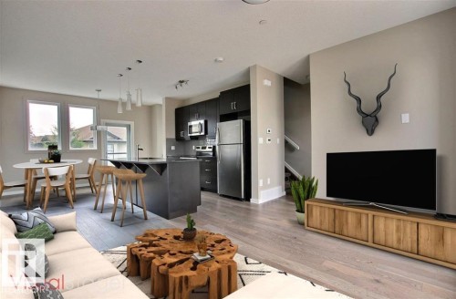 Living room with light wood-style floors and stairs - 125 1304 Rutherford Road, Edmonton, AB - Indoor Photo Showing Living Room