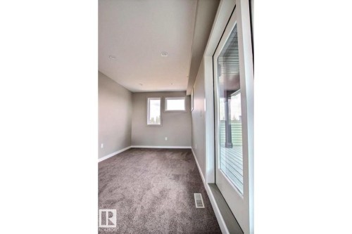 Spare room featuring dark carpet and baseboards - 125 1304 Rutherford Road, Edmonton, AB - Indoor Photo Showing Other Room