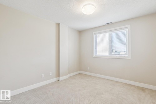 Unfurnished room featuring light carpet and a textured ceiling - 208 1350 Windermere Way, Edmonton, AB - Indoor Photo Showing Other Room