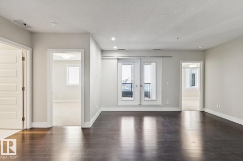 Spare room with dark wood finished floors, a textured ceiling, recessed lighting, and french doors - 208 1350 Windermere Way, Edmonton, AB - Indoor Photo Showing Other Room