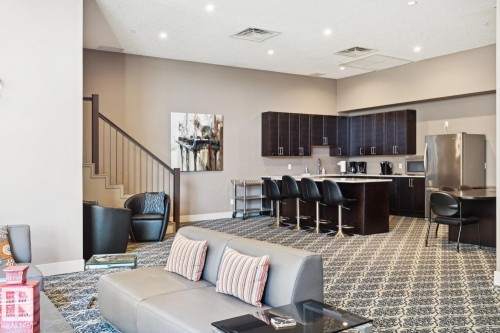 Living area featuring stairway, dark carpet, a high ceiling, and recessed lighting - 208 1350 Windermere Way, Edmonton, AB - Indoor