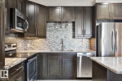 Kitchen with appliances with stainless steel finishes, dark brown cabinets, light stone countertops, and decorative backsplash - 