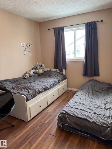 Bedroom with wood finished floors and a textured ceiling - 11 15128 22 Street, Edmonton, AB - Indoor Photo Showing Bedroom