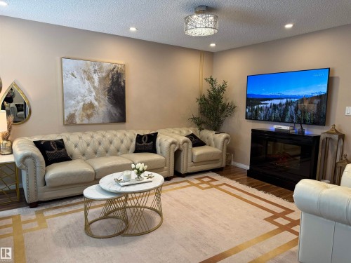 Living area with a textured ceiling, recessed lighting, wood finished floors, and a glass covered fireplace - 11 15128 22 Street, Edmonton, AB - Indoor Photo Showing Living Room With Fireplace