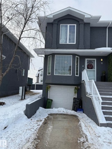 View of front of home featuring stucco siding, a garage, stairway, and a porch - 11 15128 22 Street, Edmonton, AB - Outdoor
