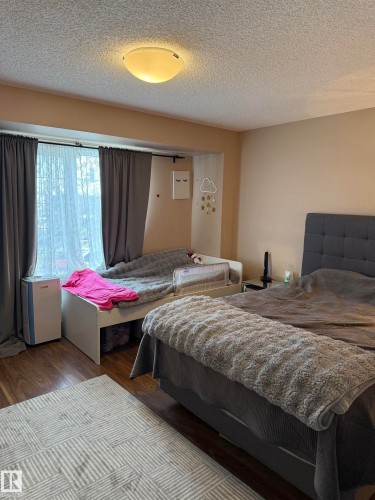 Bedroom with wood finished floors and a textured ceiling - 11 15128 22 Street, Edmonton, AB - Indoor Photo Showing Bedroom