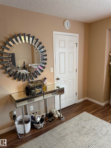 Foyer entrance featuring dark wood-type flooring and a textured ceiling - 11 15128 22 Street, Edmonton, AB - Indoor Photo Showing Other Room