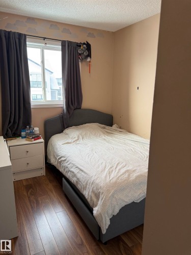 Bedroom with a textured ceiling and dark wood-style floors - 11 15128 22 Street, Edmonton, AB - Indoor Photo Showing Bedroom