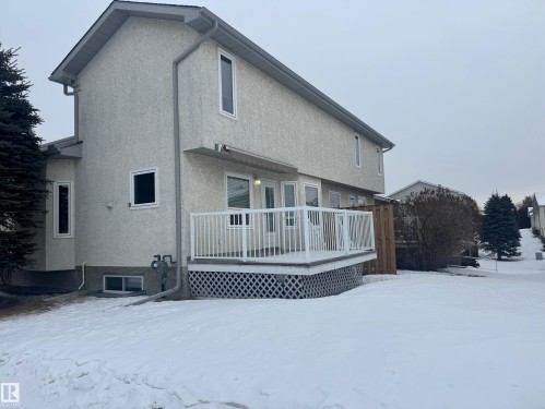 Snow covered back of property with a wooden deck and stucco siding - 6562 158 Avenue, Edmonton, AB - Outdoor With Deck Patio Veranda With Exterior