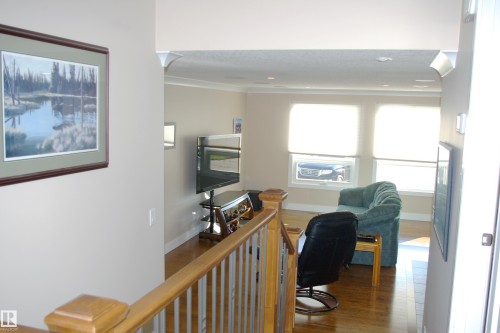 Hall featuring wood finished floors, ornamental molding, recessed lighting, an upstairs landing, and a textured ceiling - 168 Warwick Road, Edmonton, AB - Indoor