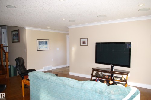 Living area featuring recessed lighting, crown molding, wood finished floors, a textured ceiling, and stairs - 168 Warwick Road, Edmonton, AB - Indoor