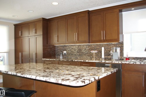 Kitchen with stainless steel dishwasher, ornamental molding, recessed lighting, light stone countertops, and a kitchen island - 168 Warwick Road, Edmonton, AB - Indoor Photo Showing Kitchen With Upgraded Kitchen