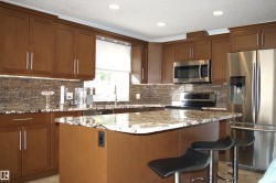 Kitchen featuring stainless steel appliances, a center island, light stone counters, recessed lighting, and a breakfast bar area - 