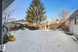 Yard layered in snow featuring a shed - 