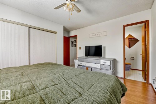 Bedroom featuring a textured ceiling, ceiling fan, wood finished floors, a closet, and ensuite bath - 11516 152A Avenue, Edmonton, AB - Indoor Photo Showing Bedroom