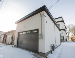 View of snowy exterior with stucco siding and a garage - 