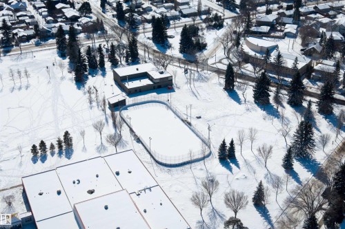 Aerial view of the surrounding area featuring snow-covered grounds, mature trees, and a community ice rink - 9127 143 Street, Edmonton, AB - Outdoor With View