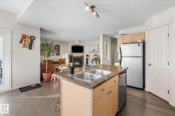 Kitchen featuring light brown cabinetry, open floor plan, a kitchen breakfast bar, appliances with stainless steel finishes, and dark wood finished floors - 