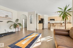 Living room featuring light wood-style floors, a textured ceiling, and arched walkways - 