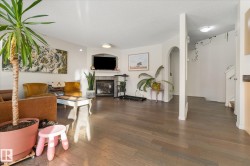 Living area featuring wood finished floors, a tile fireplace, a textured ceiling, arched walkways, and stairs - 