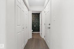 Hall featuring dark wood-style flooring, a textured ceiling, and wallpapered walls - 