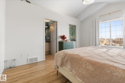 Bedroom with vaulted ceiling, light wood finished floors, and ensuite bathroom - 