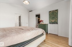 Bedroom with lofted ceiling, light wood finished floors, and ensuite bath - 