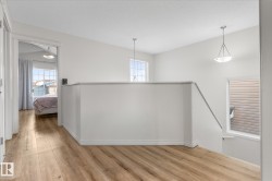 Corridor with an upstairs landing, light wood-style floors, and plenty of natural light - 