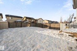 Yard layered in snow featuring a residential view, a fenced backyard, and a storage unit - 