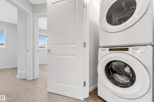 Washroom featuring stacked washer / dryer and light carpet - 2095 Maple Road, Edmonton, AB - Indoor Photo Showing Laundry Room