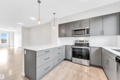 Kitchen featuring gray cabinets, appliances with stainless steel finishes, a peninsula, light wood-style floors, and pendant lighting - 2095 Maple Road, Edmonton, AB - Indoor Photo Showing Kitchen With Upgraded Kitchen