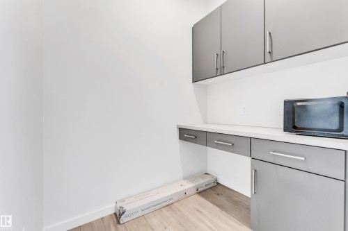 Detailed view of wood finished floors and black microwave - 2095 Maple Road, Edmonton, AB - Indoor Photo Showing Other Room