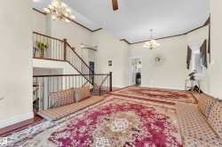 Entrance foyer featuring a chandelier, crown molding, a high ceiling, and a ceiling fan - 