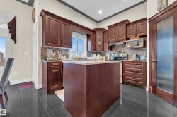 Kitchen featuring granite tiled floors, stainless steel appliances, backsplash, a kitchen island, and light stone counters - 