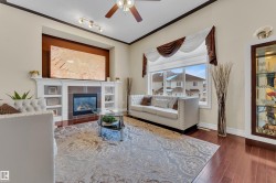 Living area featuring crown molding, a ceiling fan, dark wood-style flooring, and a tile fireplace - 