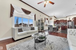 Living room with dark wood-style flooring, ornamental molding, a ceiling fan, a chandelier, and recessed lighting - 