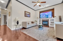 Living room with a fireplace, wood finished floors, rail lighting, ceiling fan, and ornamental molding - 