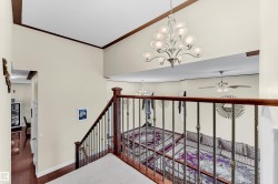 Staircase with a chandelier, wood finished floors, ceiling fan, a high ceiling, and crown molding - 