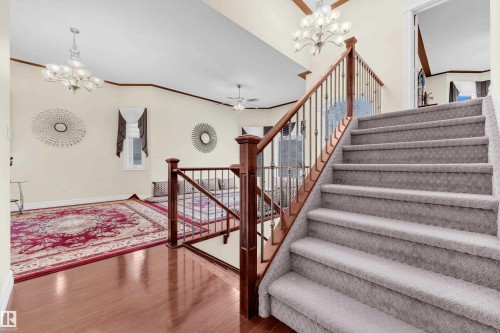 Staircase featuring a chandelier, ornamental molding, wood finished floors, and ceiling fan - 2012 69 Street, Edmonton, AB - Indoor Photo Showing Other Room