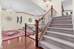 Staircase featuring a chandelier, ornamental molding, wood finished floors, and ceiling fan - 