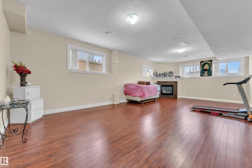 Exercise area with a fireplace, hardwood / wood-style floors, a textured ceiling, and healthy amount of natural light - 2012 69 Street, Edmonton, AB - Indoor