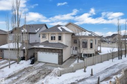 View of front of property with stucco siding, a shingled roof, a garage, and stone siding - 