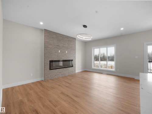 Unfurnished living room with light wood-style floors, a fireplace, healthy amount of natural light, and recessed lighting - 46 Waverly Way, Fort Saskatchewan, AB - Indoor Photo Showing Living Room With Fireplace