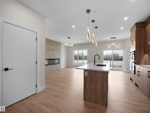 Kitchen with a kitchen island with sink, open floor plan, decorative light fixtures, modern cabinets, and light wood finished floors - 46 Waverly Way, Fort Saskatchewan, AB - Indoor Photo Showing Kitchen