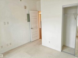 Unfurnished bedroom with a closet, light colored carpet, and electric panel - 