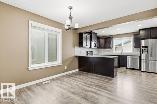 Kitchen with appliances with stainless steel finishes, a chandelier, decorative light fixtures, dark brown cabinetry, and backsplash - 2 Wingate Way, Fort Saskatchewan, AB - Indoor Photo Showing Kitchen